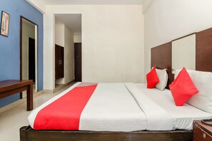 A hotel room with a bed, a wooden headboard, a mirror, and a bench. - OYO 9386 Begumpet (Hyderabad)