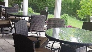 A patio area with wicker furniture and a glass table, surrounded by greenery. - Elit Palace Hotel & Spa (Balchik)