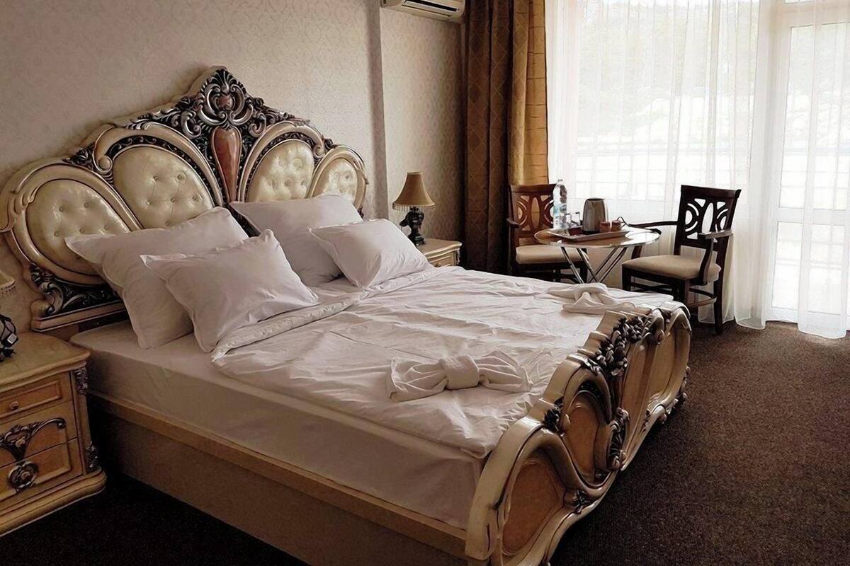 A hotel room with a large bed, a desk, a chair, and a window with curtains.