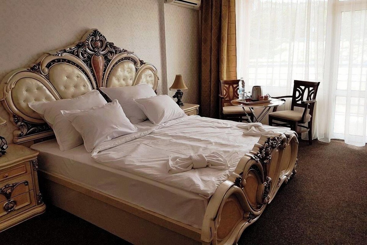 Une chambre d’hôtel avec un grand lit, un bureau, une chaise et une fenêtre avec des rideaux.