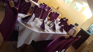 A dining table set with purple chairs, white tablecloth, and silverware. - Elit Palace Hotel & Spa (Balchik)