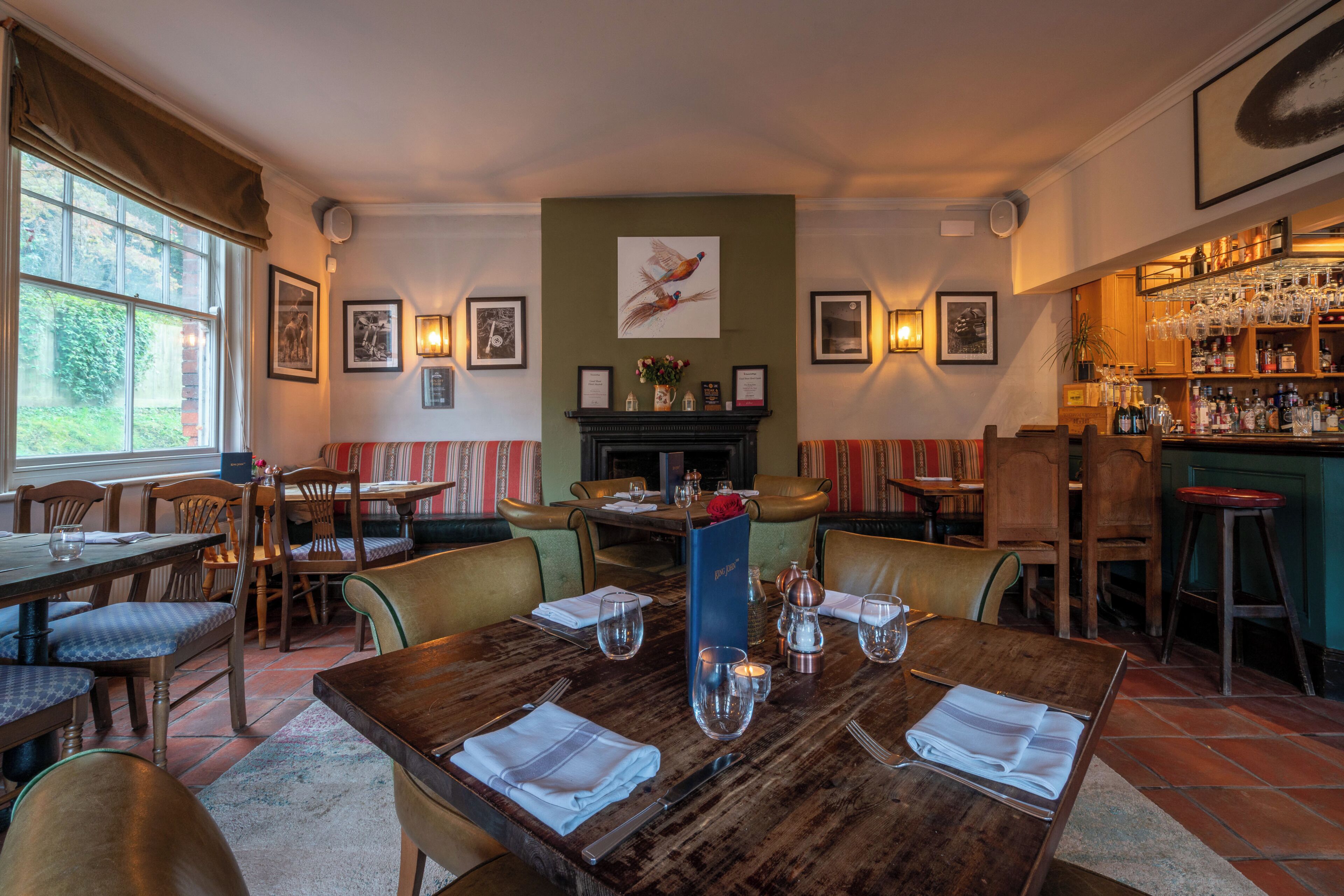 Un ristorante con camino, quadri appesi e zona bar.