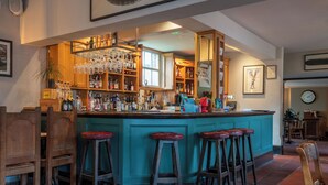 A bar area with stools, shelves of bottles, and a clock on the wall. - King John Inn (Salisbury)