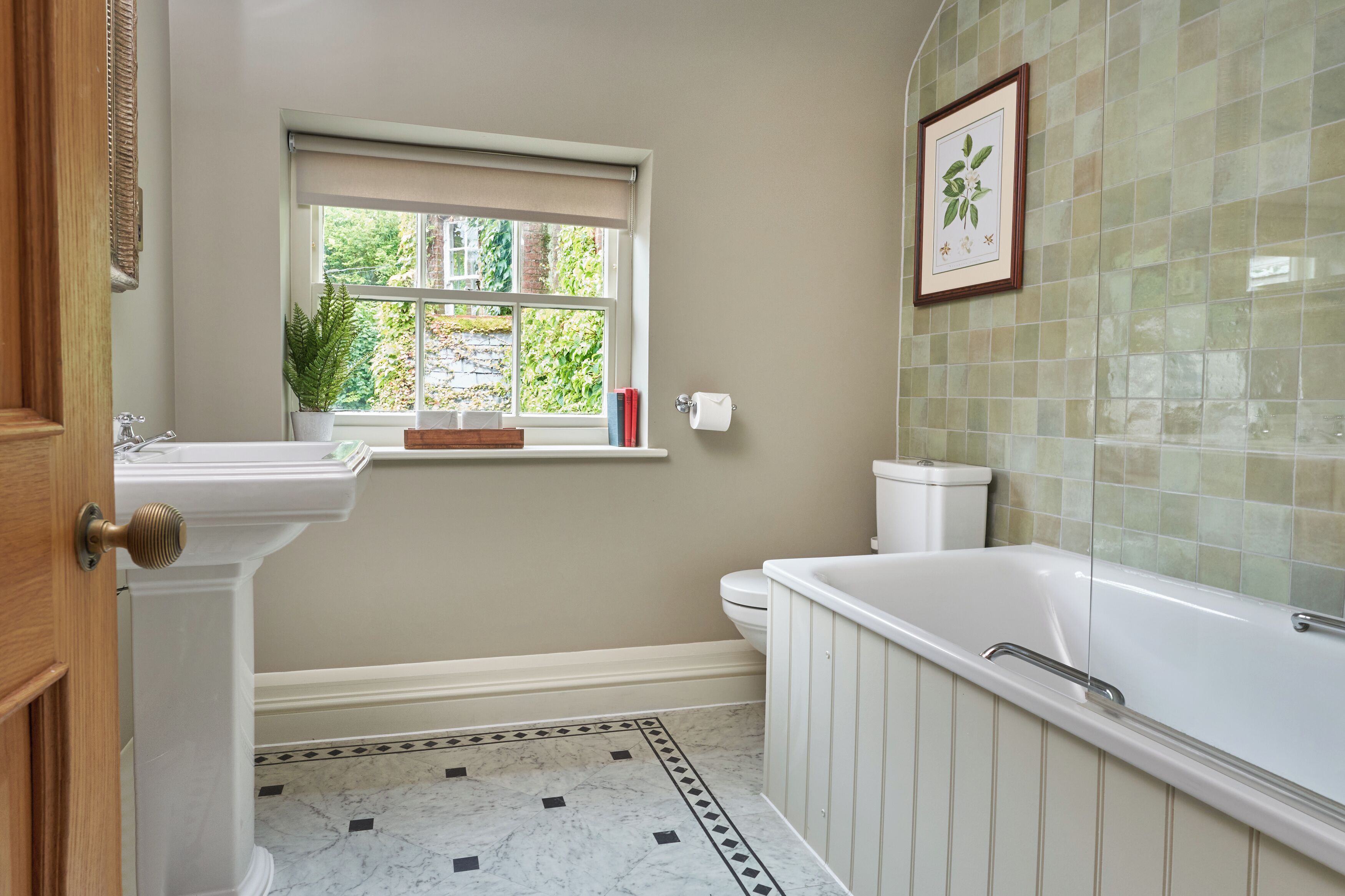 A bathroom with a window, a sink, a toilet, and a bathtub.