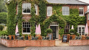A brick building with ivy covering the walls, a sign reading 'King John,' outdoor seating with umbrellas, and a chalkboard menu. - King John Inn (Salisbury)