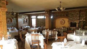 Um restaurante com paredes de pedra, mesas de madeira e lareira.