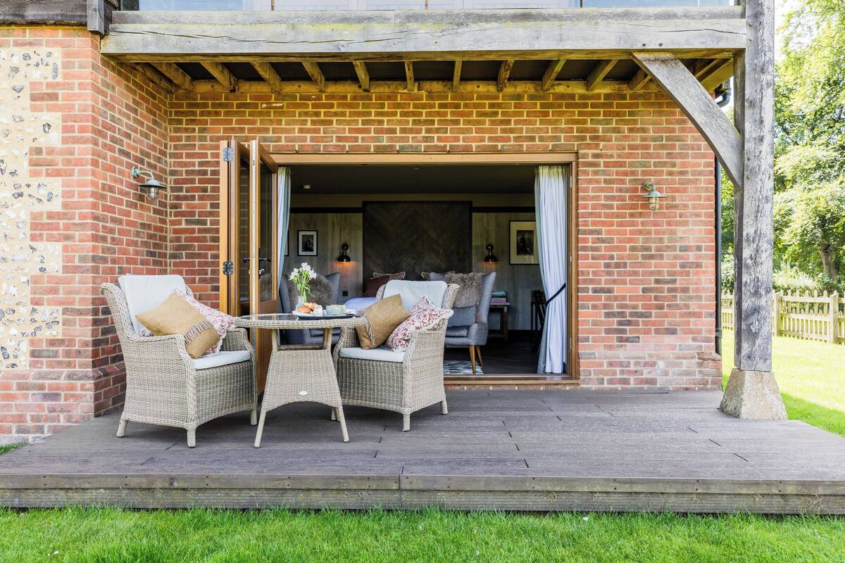 A patio with wicker furniture and a brick wall.