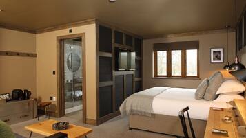 A bedroom with a bed, a desk, a chair, a small table, a coffee maker, and a window.