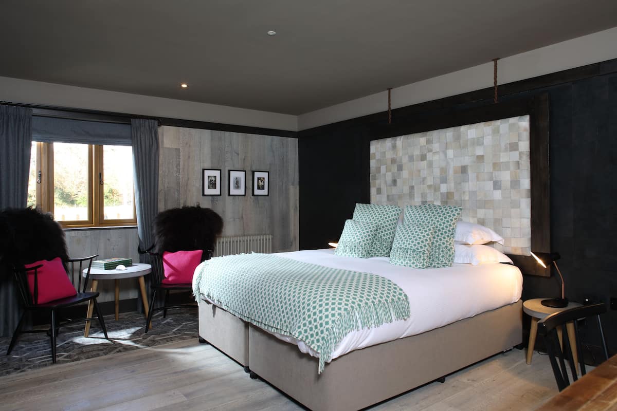 A modern bedroom with a large bed, a round table, and two chairs.