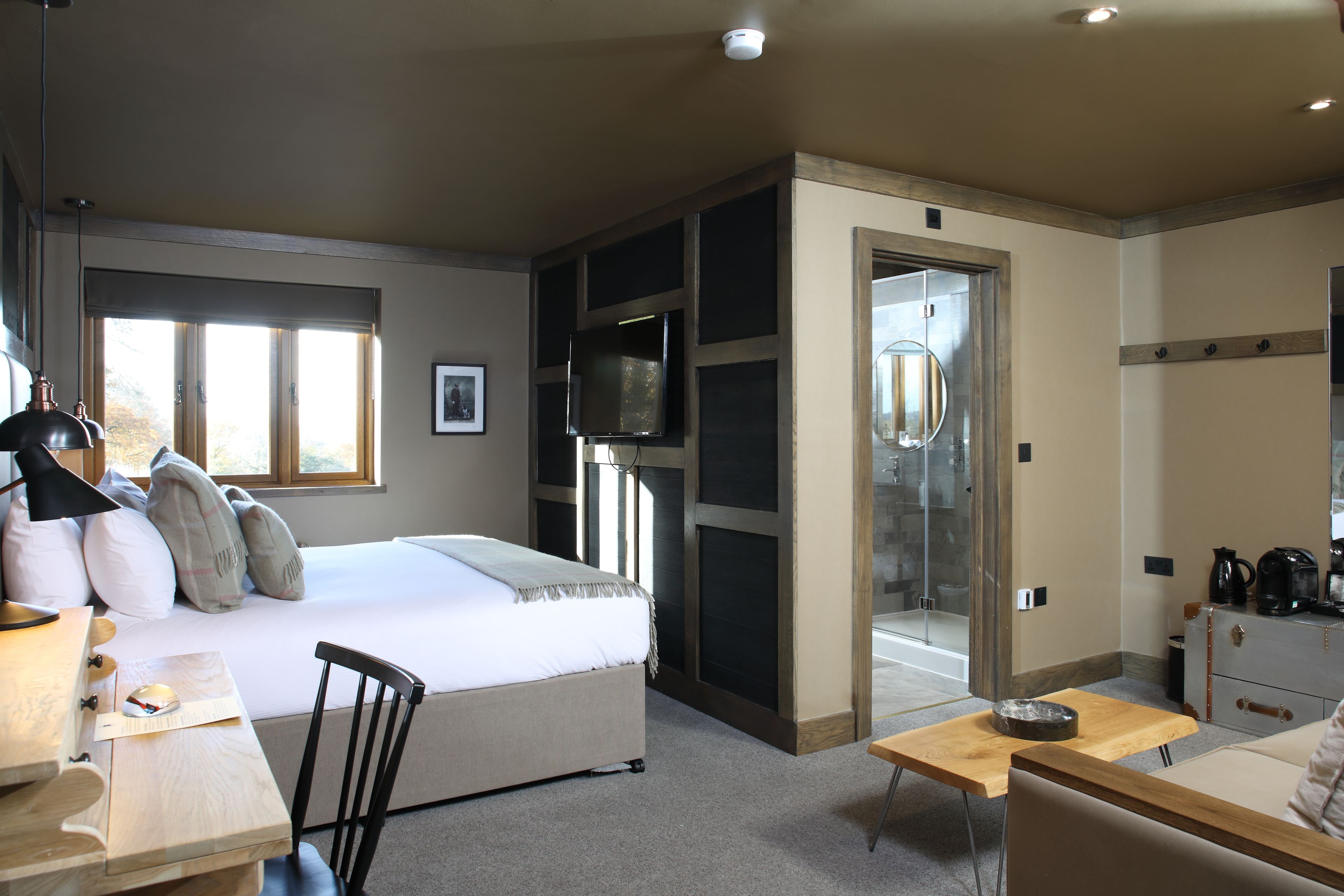Habitación de hotel con cama, escritorio, silla y una puerta corredera que da a un baño.