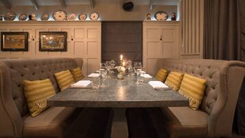 A formal dining room with a marble table, cushioned chairs, and a decorative backdrop.