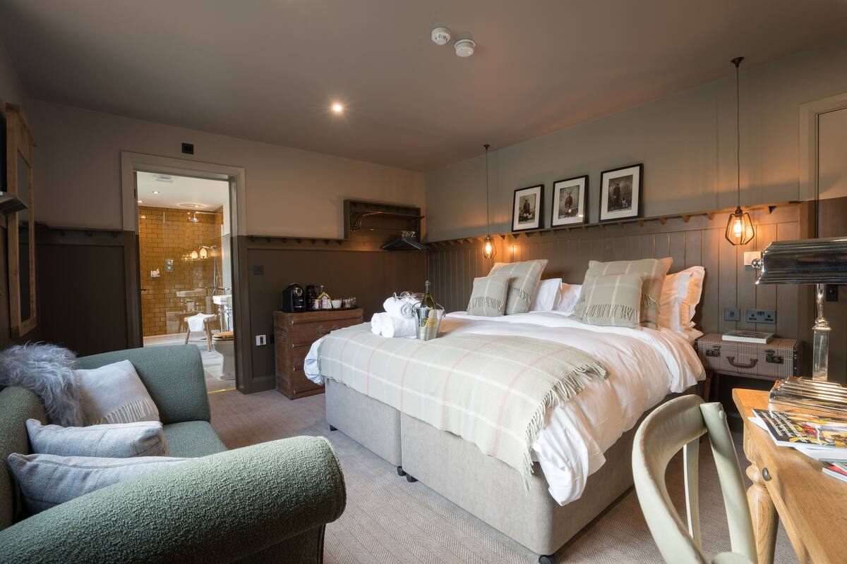 A bedroom with a large bed, a sofa, a desk, and a wardrobe.