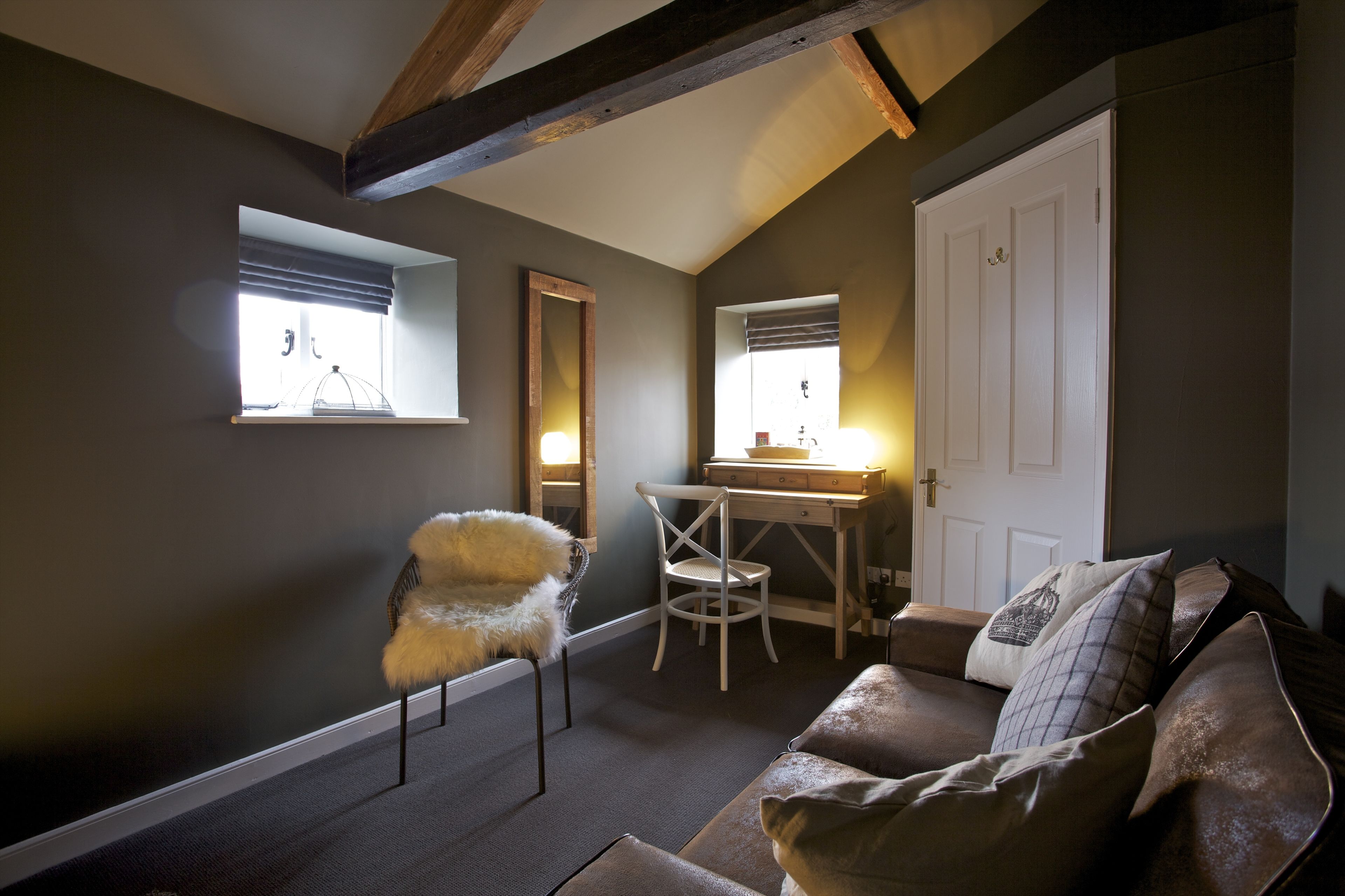 A cozy room with a sofa, a chair, a desk, and a wardrobe.