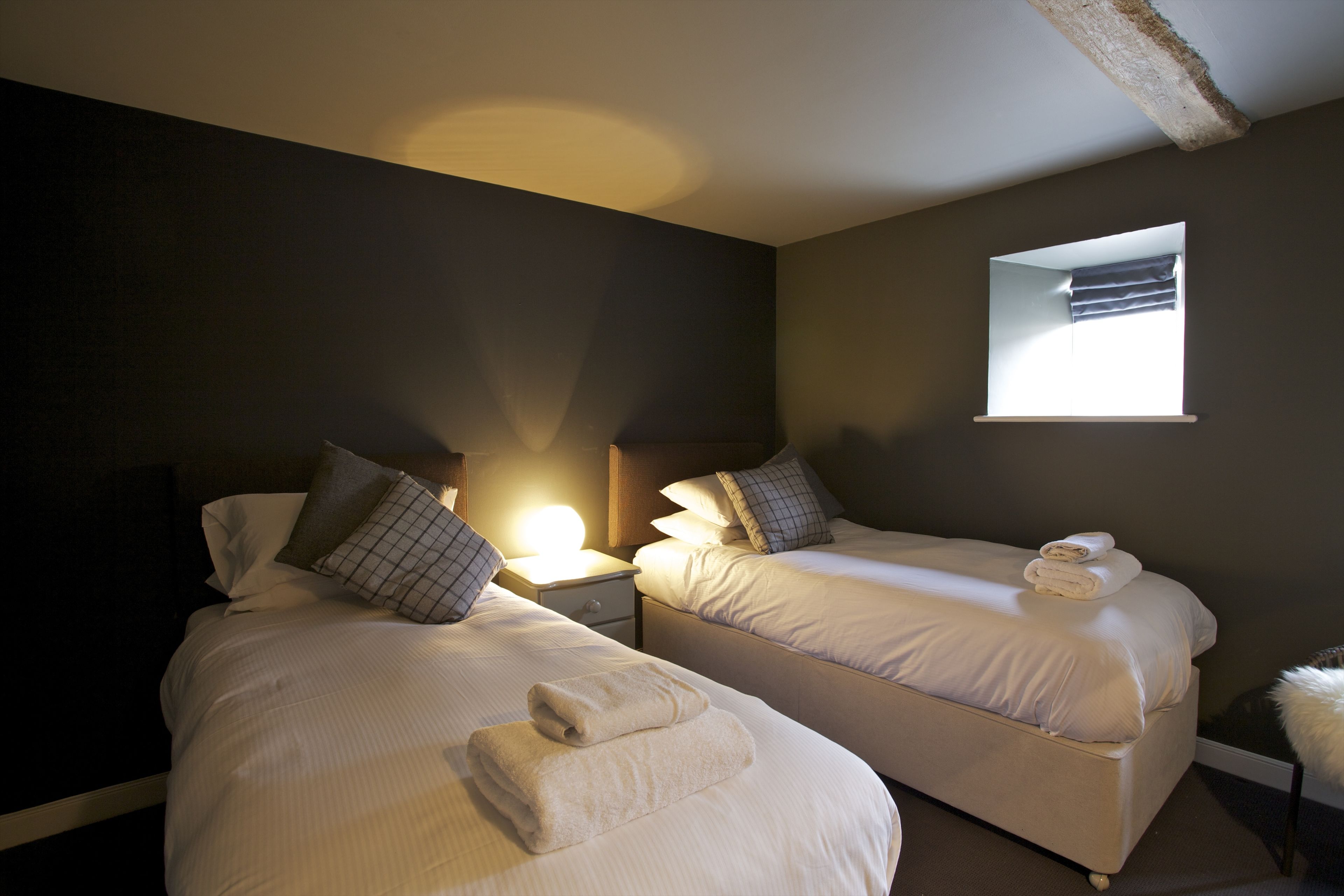 Habitación de hotel con dos camas, una mesita de noche, un ventanal y un espejo.