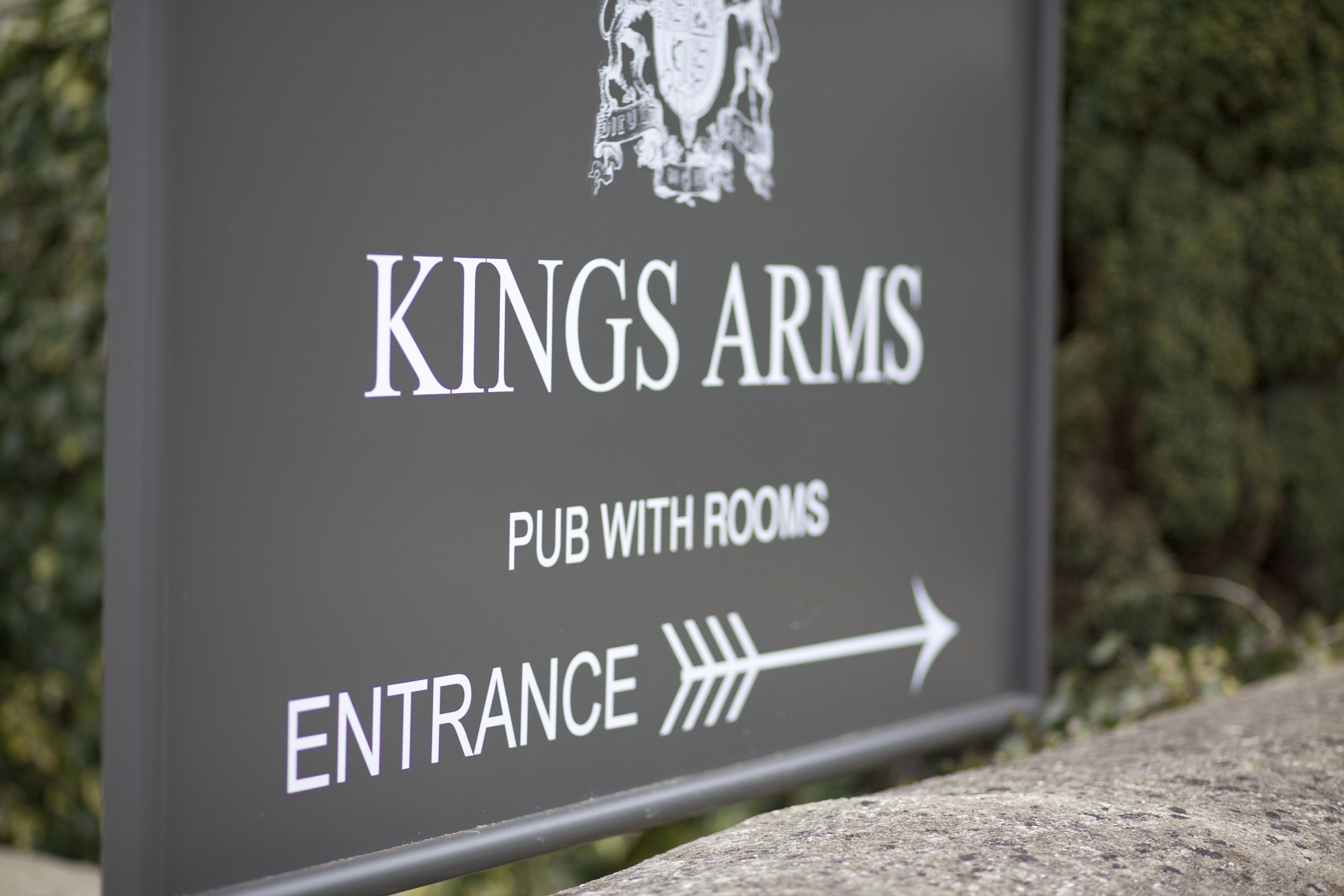 Señalización para el pub con habitaciones 'Kings Arms Pub' con una flecha indicando la entrada.