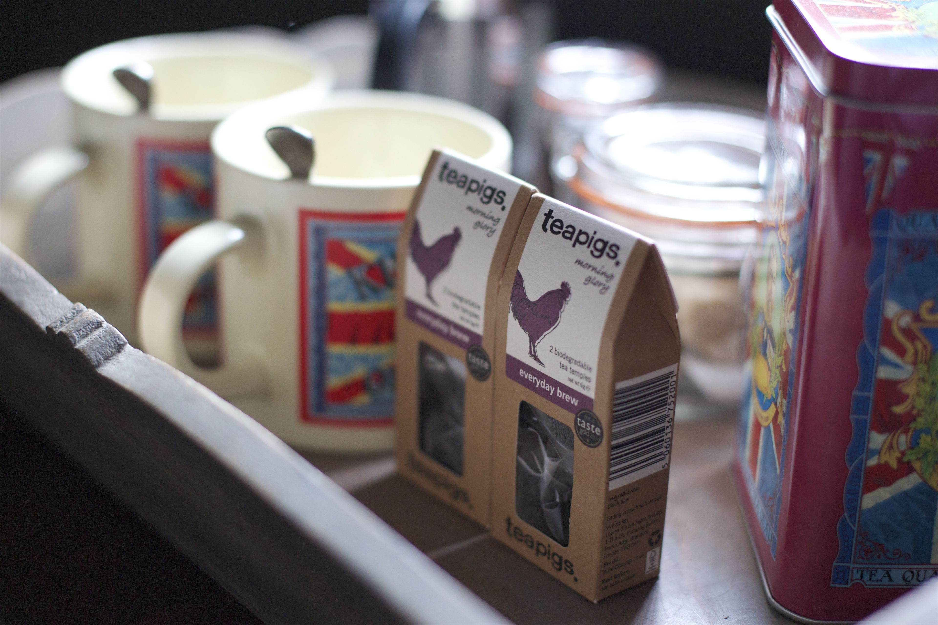 A shelf with various tea products, including teapigs tea bags and a red tea canister.