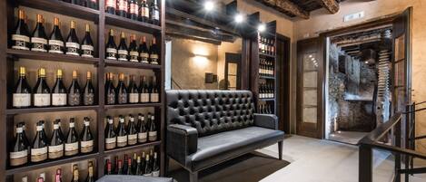 Une cave à vin avec des étagères remplies de bouteilles, un canapé en cuir et un mur en pierre.