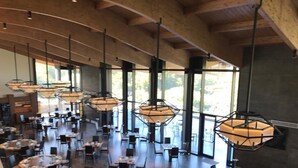A spacious dining area with multiple tables and chairs, large windows, and hanging pendant lights. - Cavanera Etnea Resort & Wine Experience (Castiglione di Sicilia)