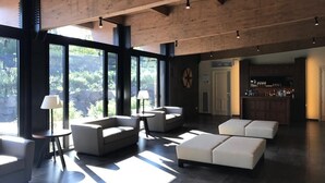 A spacious living area with large windows, a bar area, and modern furniture. - Cavanera Etnea Resort & Wine Experience (Castiglione di Sicilia)
