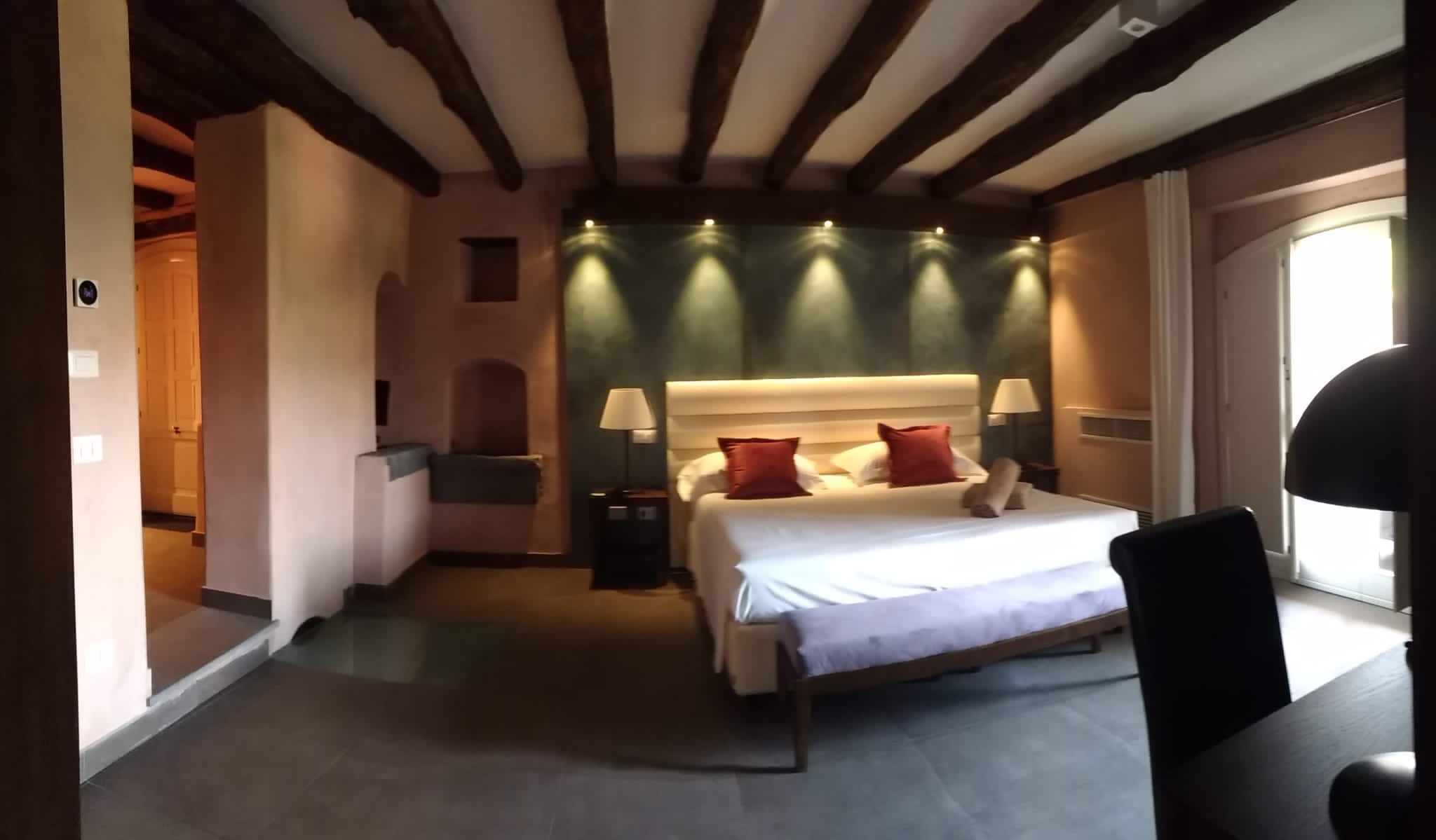 Una habitación de hotel con cama, mesitas de noche, lámparas, una silla y vista al mar.