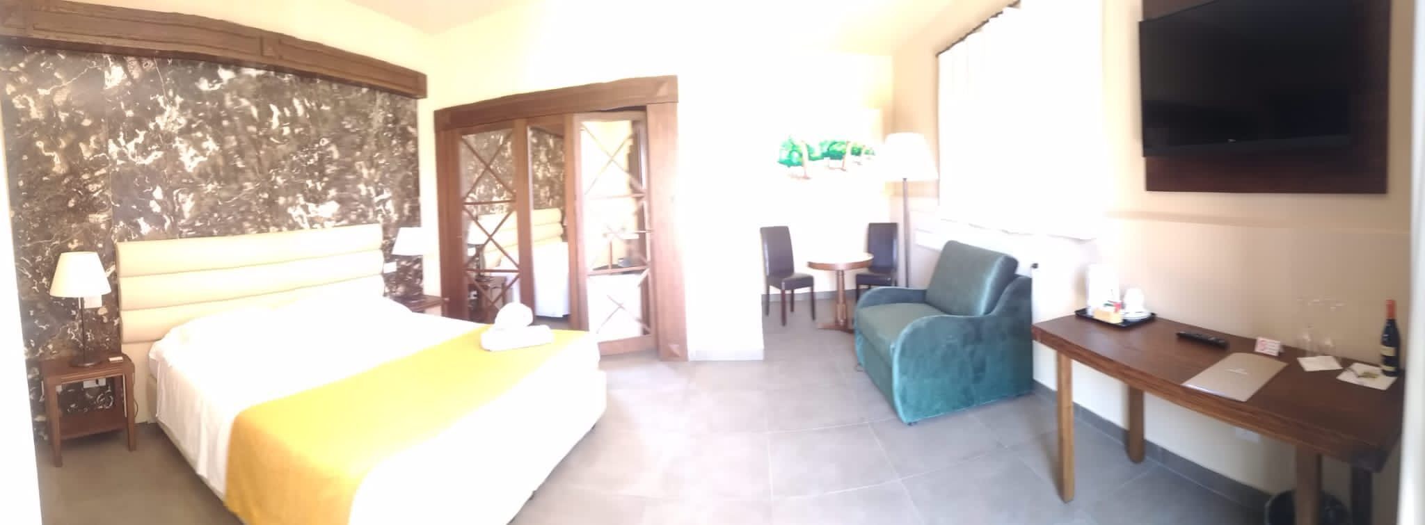 A hotel room with a bed, a desk, a chair, and a TV.