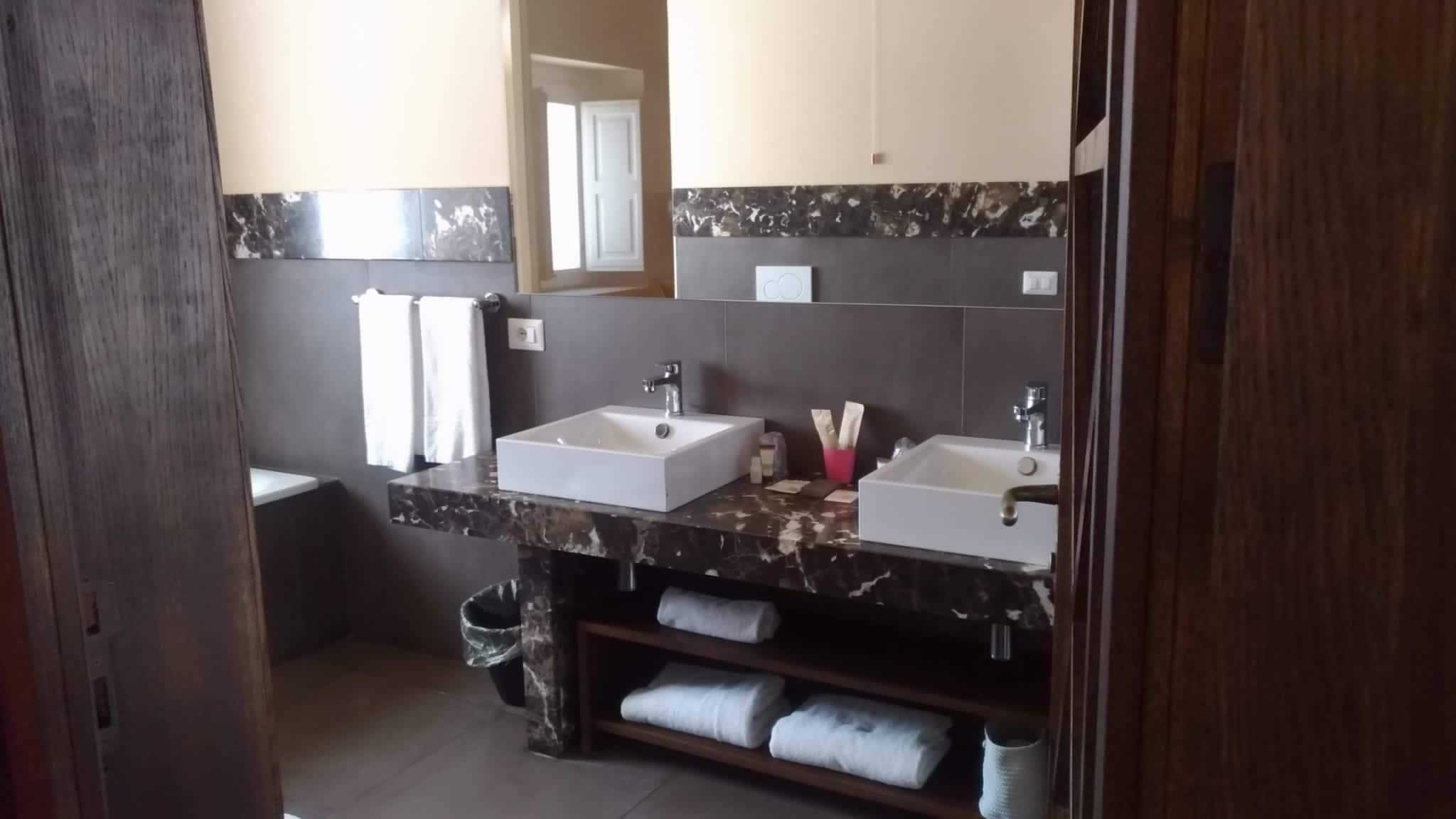 A bathroom with two sinks, a mirror, and a towel rack.