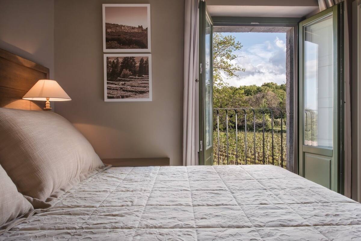 A bedroom with a bed, a nightstand, a lamp, and two framed pictures on the wall.