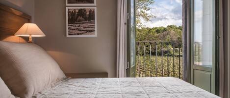 Un dormitorio con una cama, una mesita de noche, una lámpara y dos cuadros en la pared.