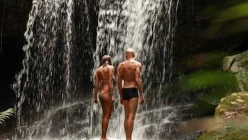 Duas pessoas em frente à base de uma cachoeira.