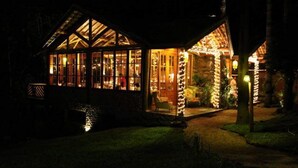 Una casa acollidora i ben il·luminada, amb grans finestres i un porxo atractiu, envoltada d'un jardí.
