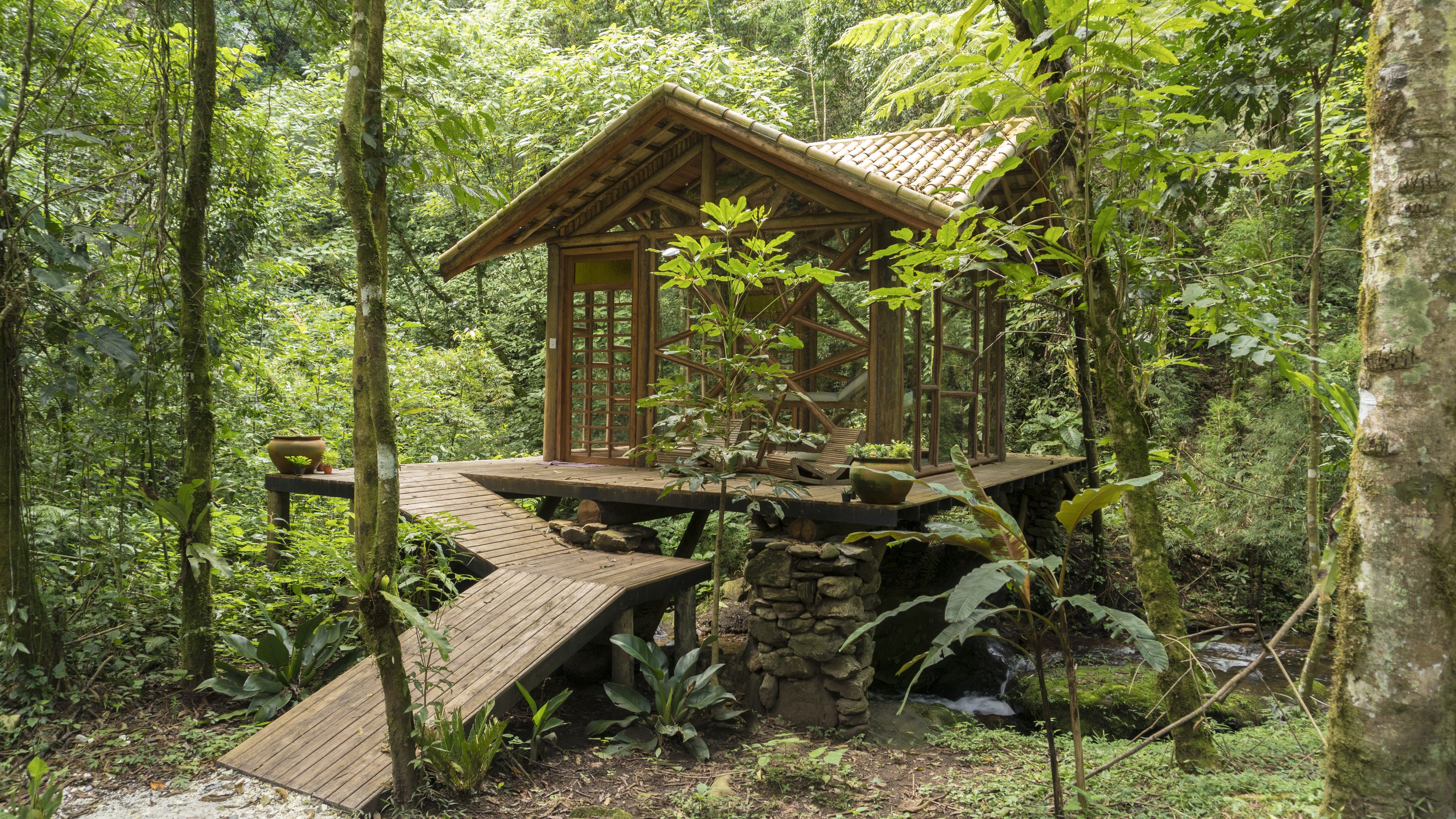 A wooden cabin with a sloped roof, built on stilts in a forested area.