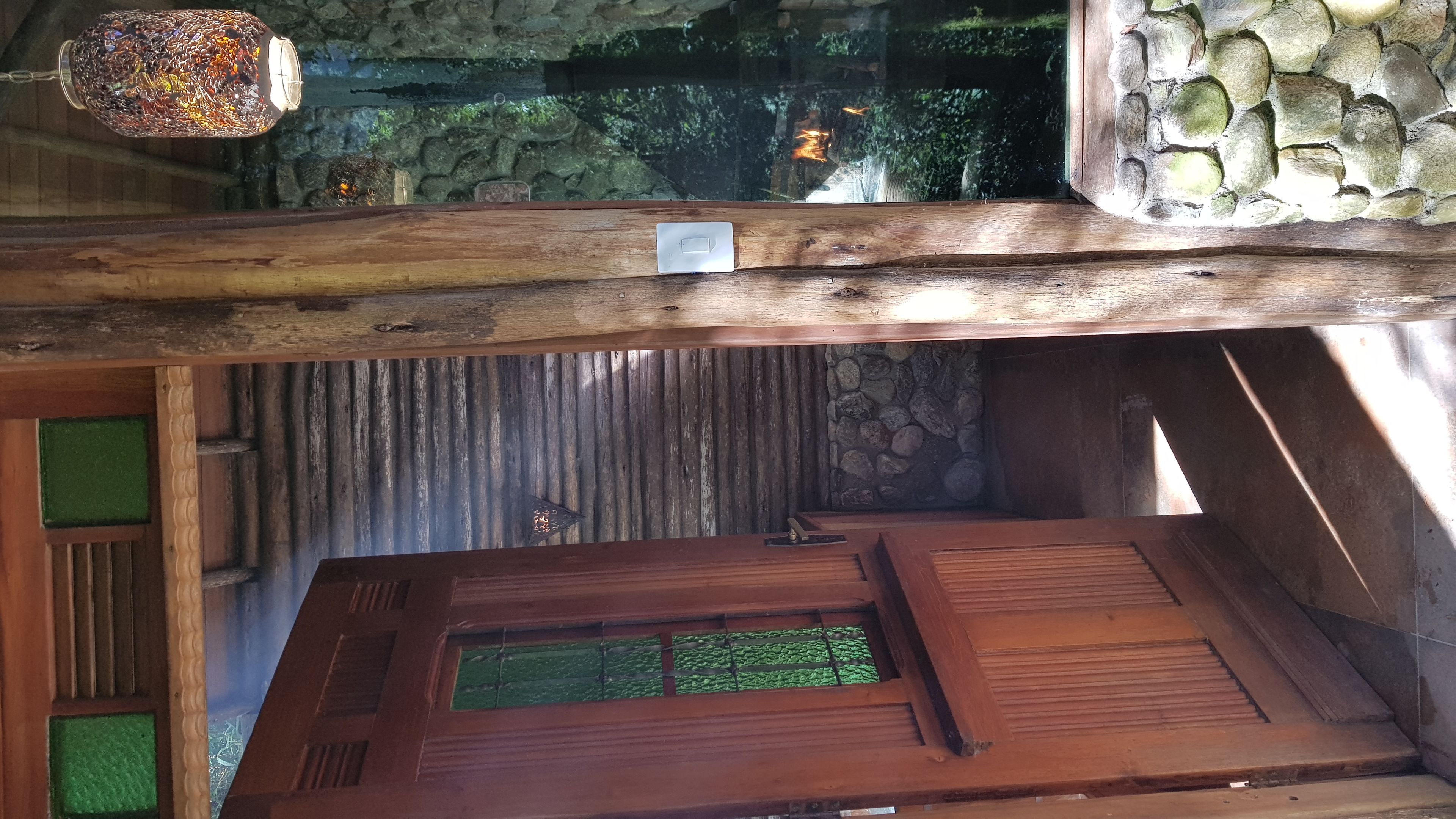 A wooden interior with a stone wall, a wooden ceiling, and a green panel.