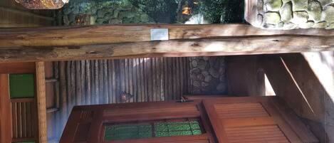 A wooden interior with a stone wall, a wooden ceiling, and a green panel.