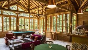 Una habitació àmplia amb billar, seients confortables i grans finestres que ofereixen vistes a l'exterior.