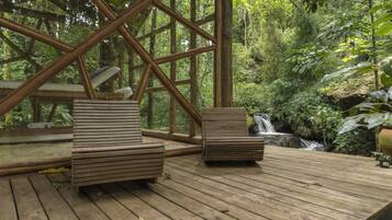 Relax on the deck surrounded by lush forest and a soothing waterfall.
