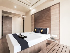 Una habitación de hotel moderna con una cama grande, una mesita de noche y un armario empotrado.
