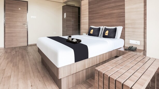 A modern hotel room with a large bed, a bedside table, a desk, and a wardrobe. - Hotel Mahadev Residency (Bhiwandi)