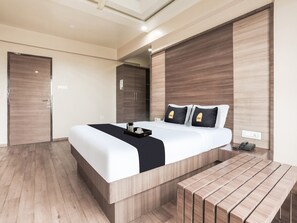 Una habitación de hotel moderna con una cama grande, una mesita de noche, un escritorio y un armario.
