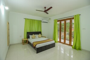A bedroom with a bed, a ceiling fan, an air conditioning unit, and a sliding glass door. - OYO 10297 Home Sunset View 2BHK Dona Paula (Panaji)