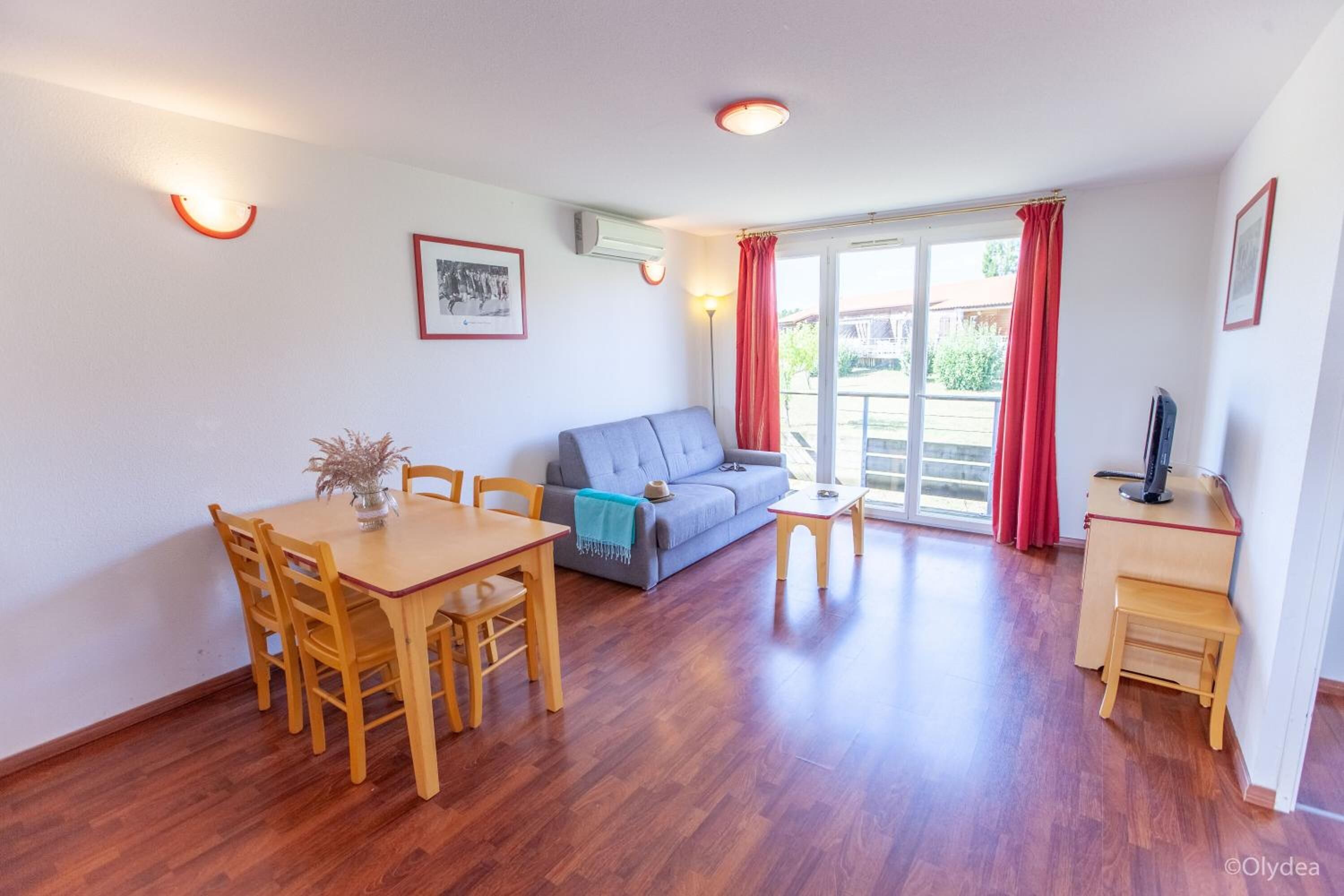 Een kamer met een houten eettafel, stoelen, een bank, een bijzettafeltje en een tv-meubel.