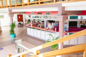 Un vestíbulo de hotel con mostrador de recepción, zona de estar y una escalera.