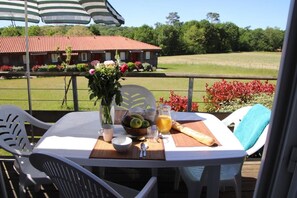 A table set outdoors with a view of a house and fields. - Olydea Cassen (Cassen)