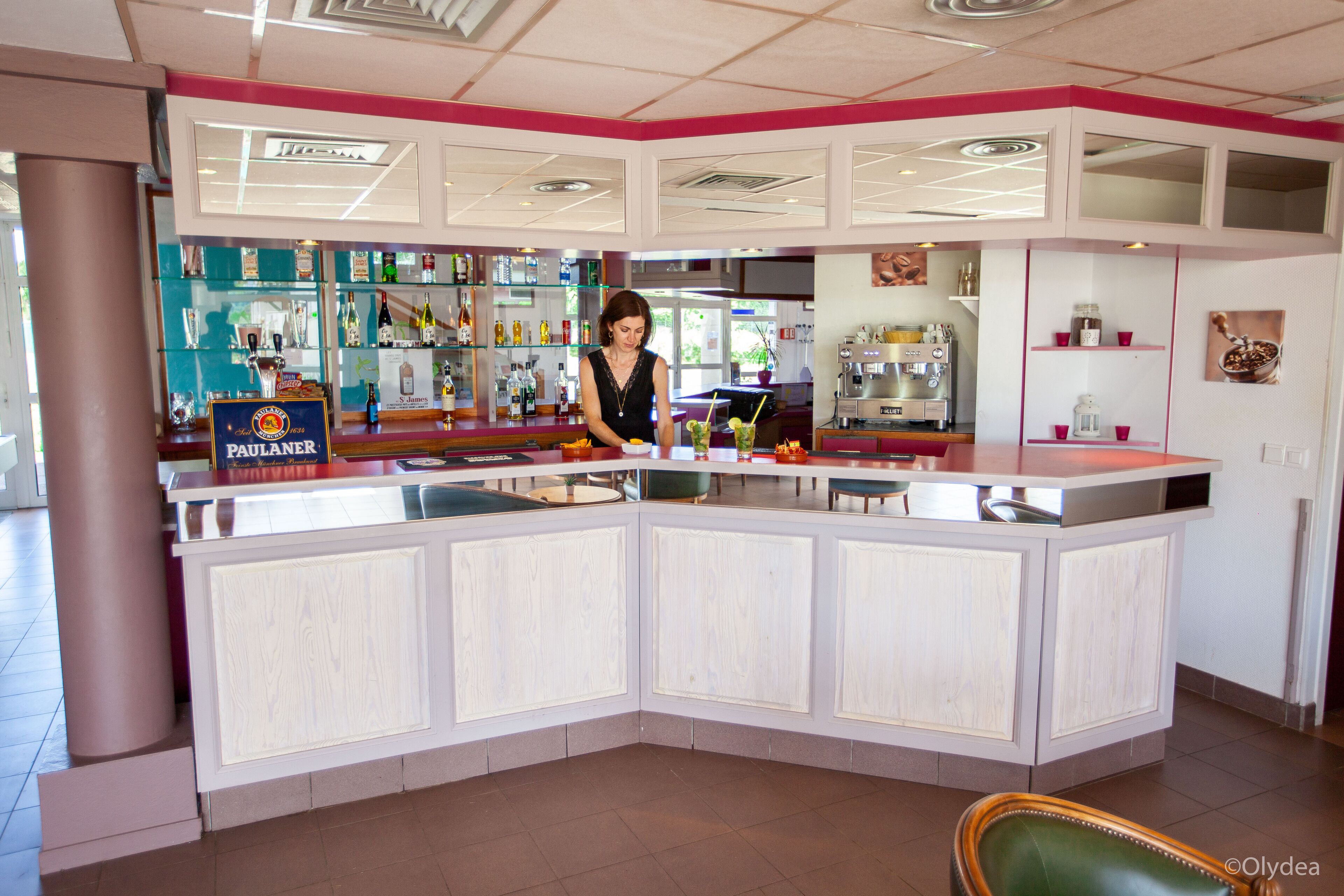 Un espace bar avec un comptoir, des étagères remplies de bouteilles et un appareil à café.