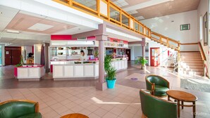 A spacious lobby with a central reception desk, a staircase, and seating areas. - Olydea Cassen (Cassen)
