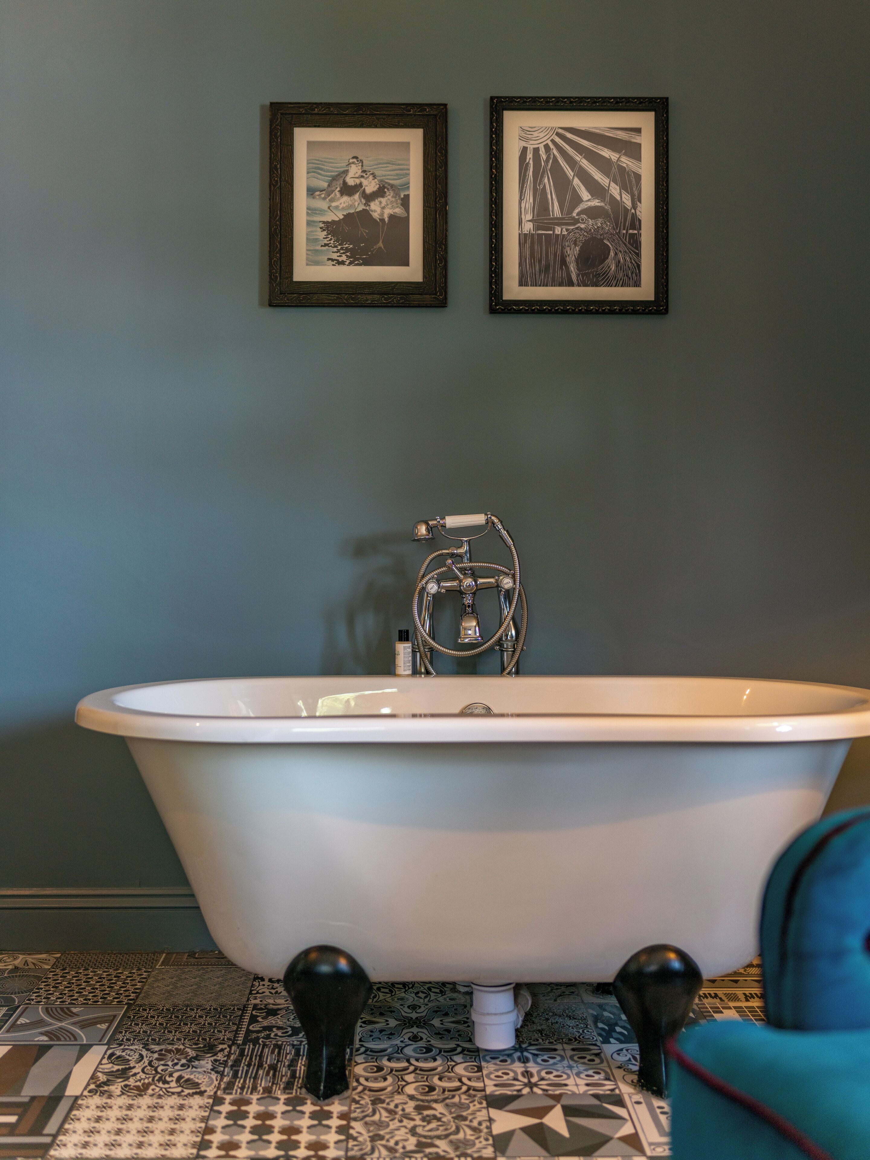 A bathroom with a freestanding bathtub, a towel rack, and a patterned floor.