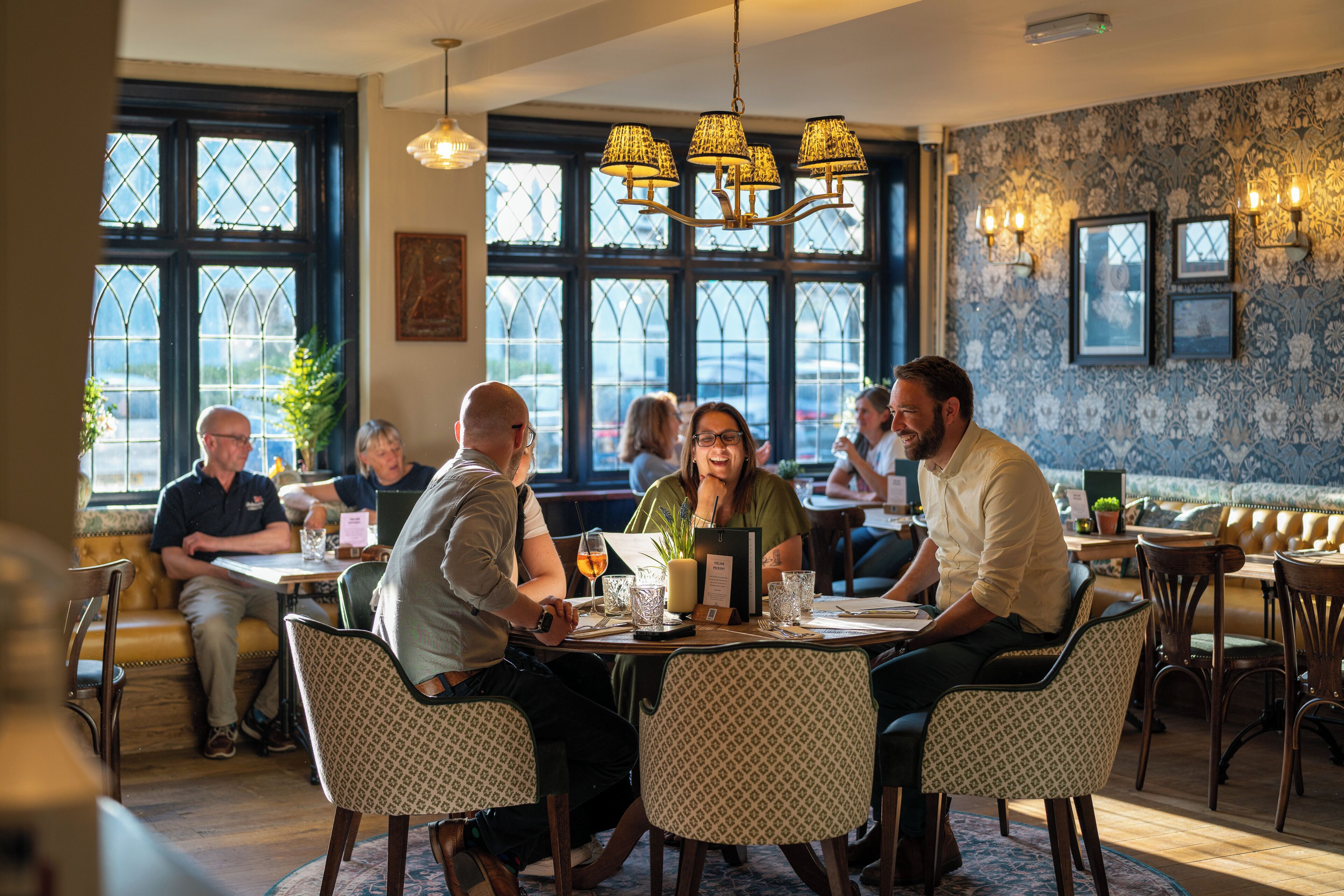 Un restaurant où un groupe de personnes est assis à une table, entouré de chaises à motifs.