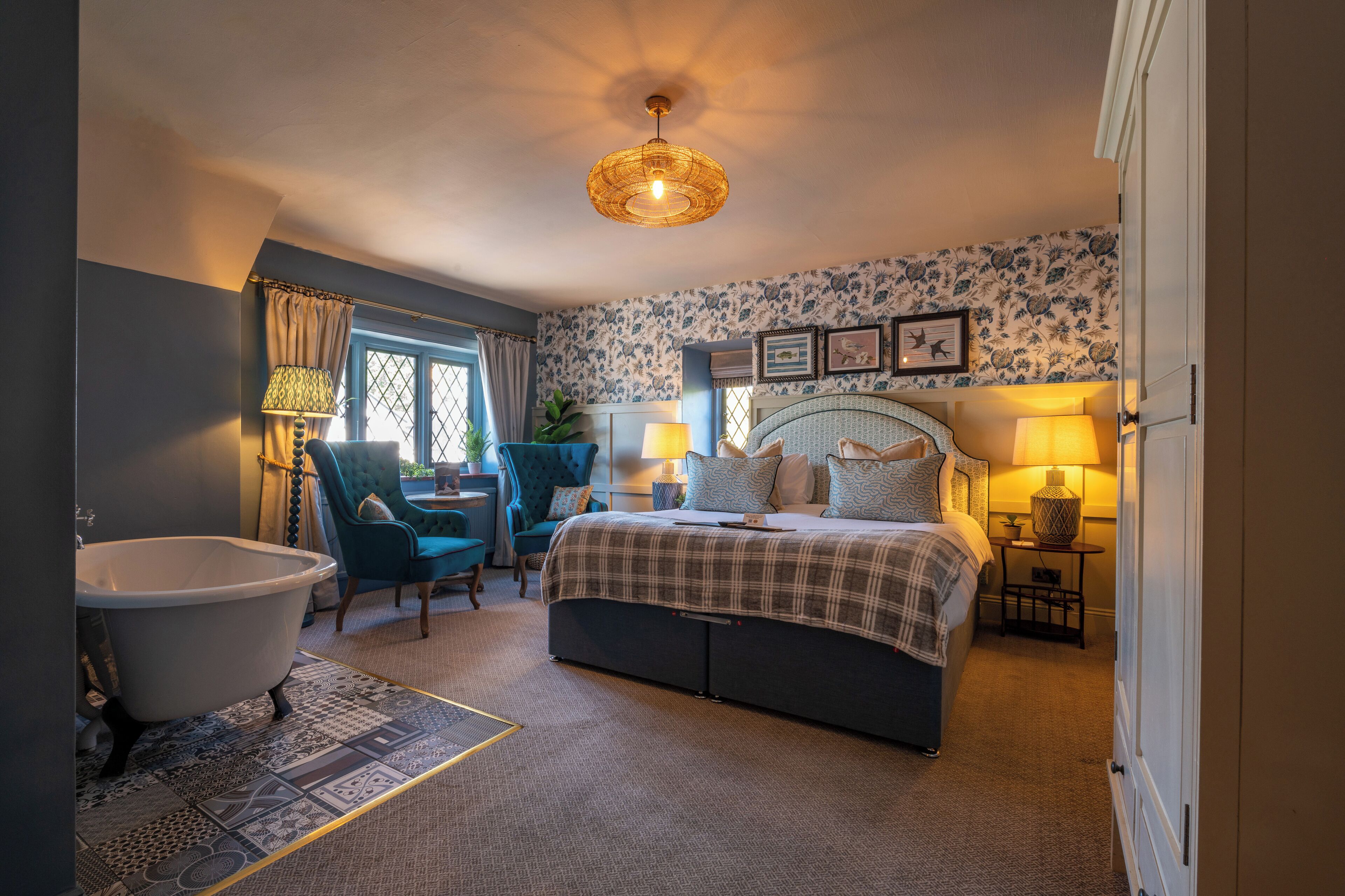 A bedroom with a large bed, a bathtub, a chair, and a desk.