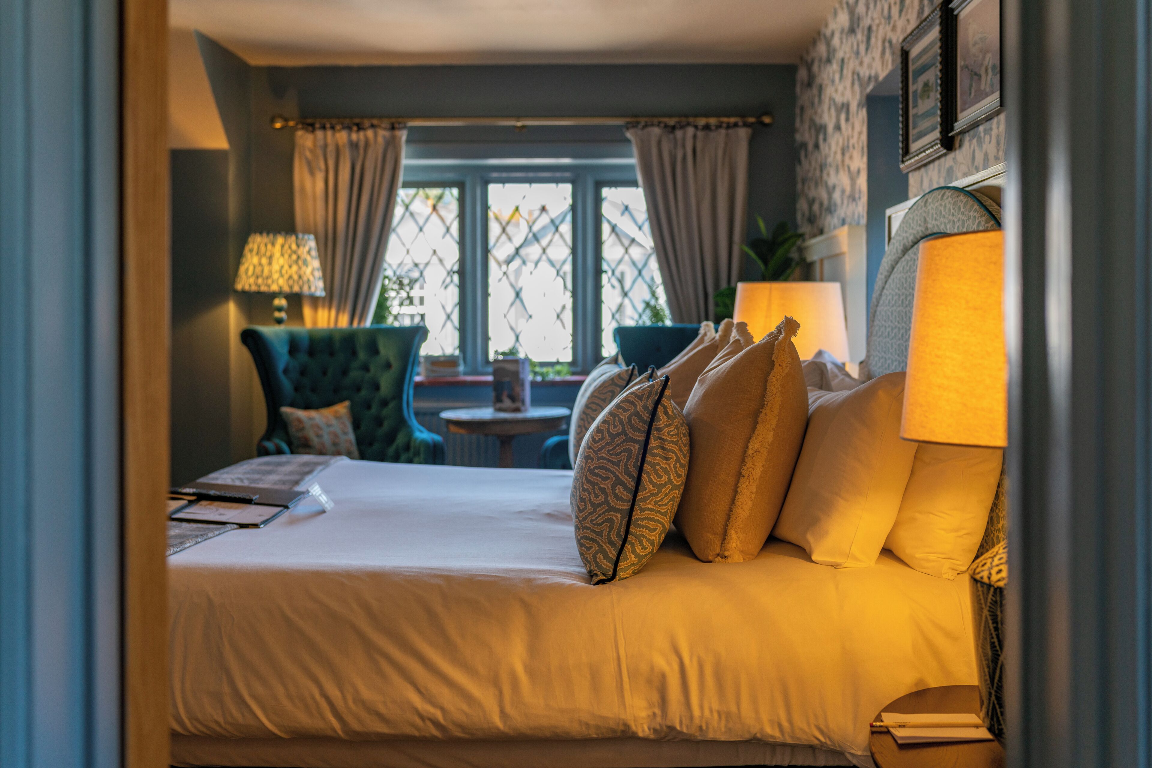 A hotel room with a bed, a chair, a table, and a window with curtains.