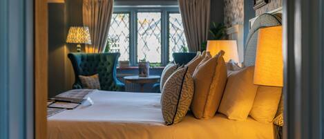 A hotel room with a bed, a chair, a table, and a window with curtains.