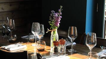 Una mesa de comedor dispuesta con copas de vino, un florero con flores y condimentos.